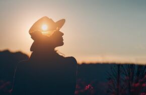 Frau sitzt im Sonnenuntergang, schaut in die Ferne und möchte endlich loslassen können