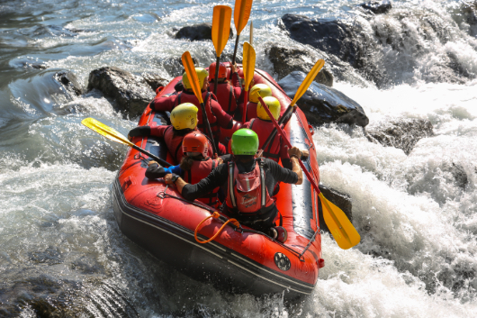 Psychologische Sicherheit fördert ein Team von Menschen in einem Schlauchboot beim Rafting.